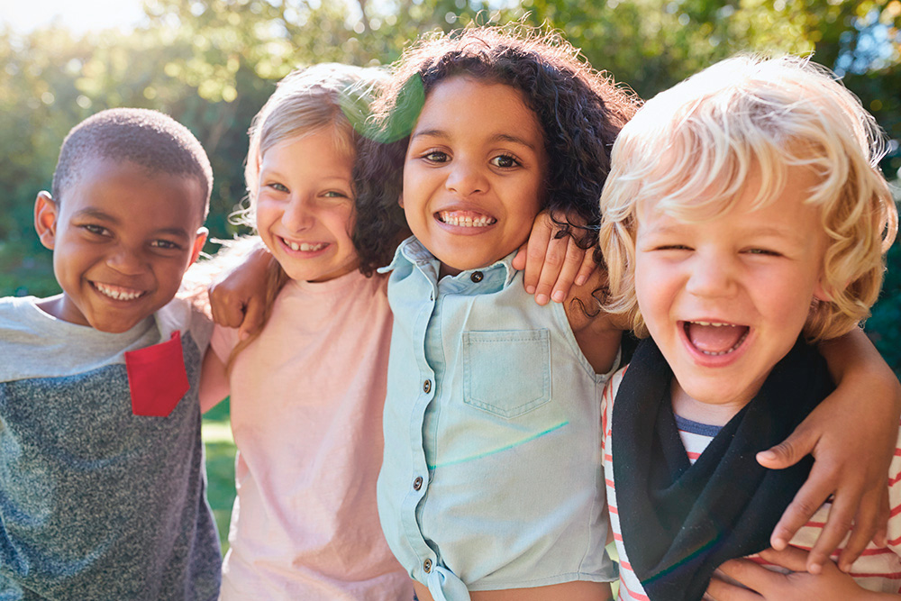 A group of joyful children smiling and posing together, showcasing their happiness and social connection.