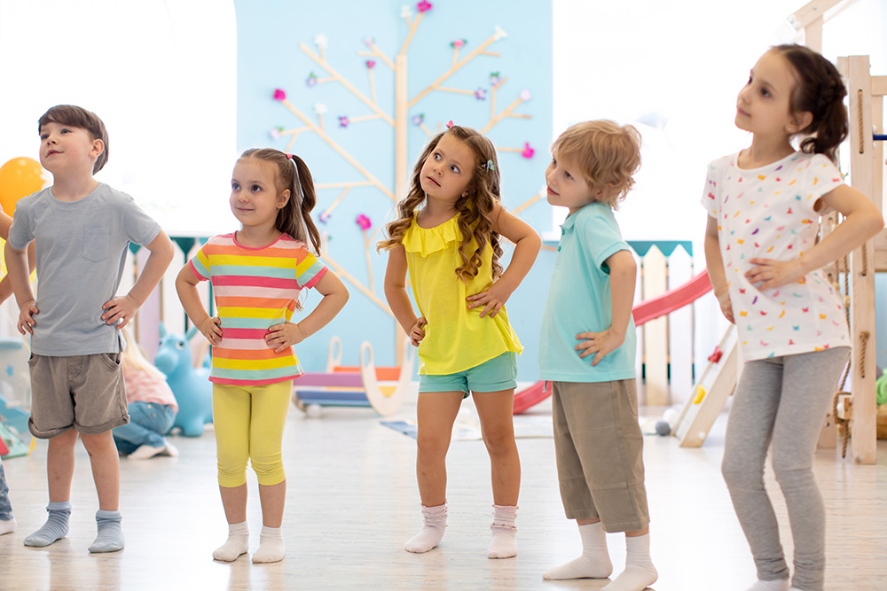 A group of children standing in a line within a classroom, participating in an exercise designed to enhance their skills.