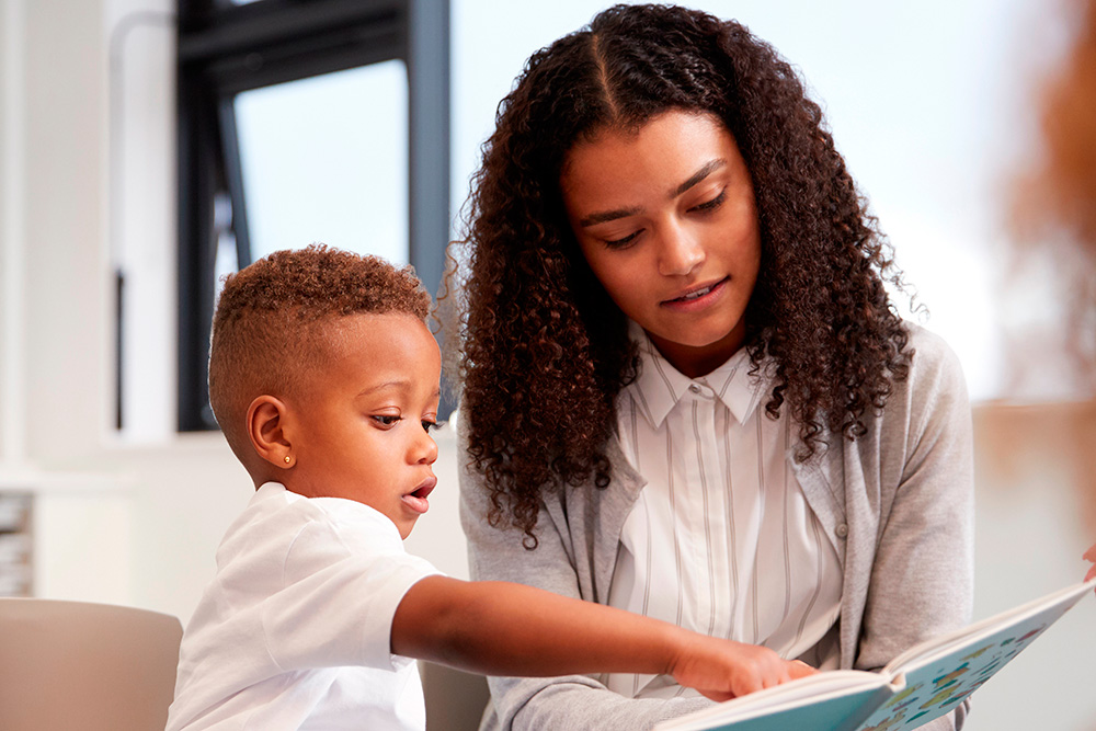 A teacher and a child engage in reading a book together, highlighting the joy of shared storytelling and education.